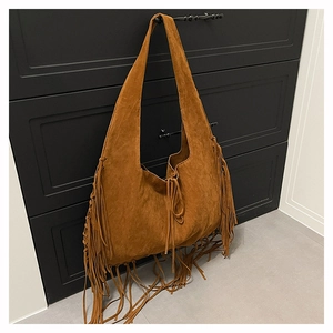 Detailed view of bohemian brown suede tote bag with long fringe accents on cabinet