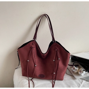Détail du sac cabas en daim bordeaux avec pompons à cordon et longues bandoulières