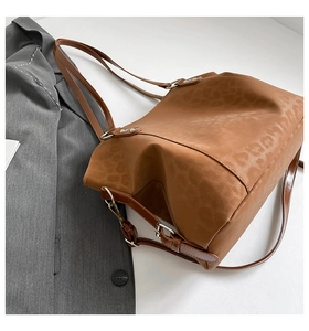 Detail of leopard embossed texture and silver hardware on a brown faux leather tote bag