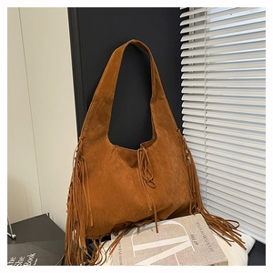 Close-up of bohemian brown suede tote bag featuring long decorative fringe and wide strap