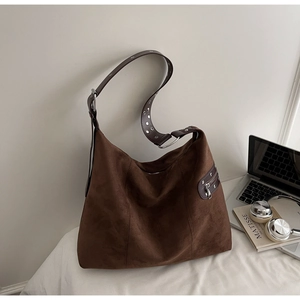 Detail of a brown suede hobo bag with silver eyelet wide strap and large capacity