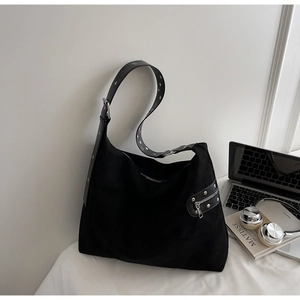 Detail of black suede messenger bag with silver eyelets and side zipper pocket