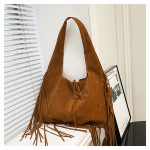 Brown faux suede hobo bag with long fringes displayed in a minimalist indoor setting