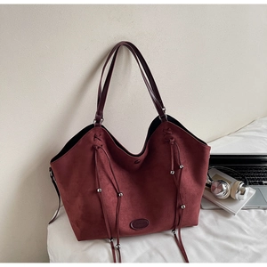 Détail du sac cabas en daim bordeaux avec pompons à franges et perles métalliques