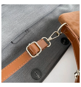 Detail of brown PU leather strap with golden lobster clasp and metal adjustment buckle