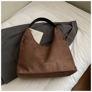 Detail der dunkelbraunen Wildleder-Schultertasche mit Metallnieten am breiten Gurt