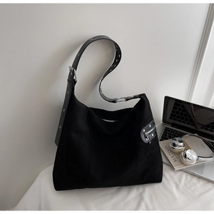 Detail of wide shoulder strap with silver eyelets on black suede hobo bag