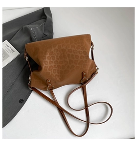 Close-up of brown leopard print tote bag with silver metal ring and rivet strap details