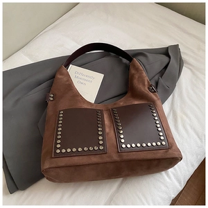 Nahaufnahme der braunen Wildledertasche mit Nieten auf einem grauen Blazer-Hintergrund