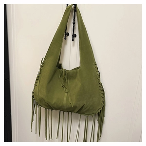 Close-up of olive green suede tote bag featuring bohemian tassels and braided side details