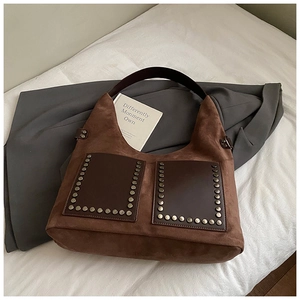 Detailaufnahme der braunen Wildledertasche mit dekorativen Nieten und Ledertaschen