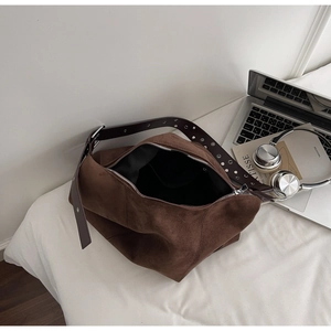 Detailed shot of brown suede tote bag featuring rivet straps and silver metal zipper