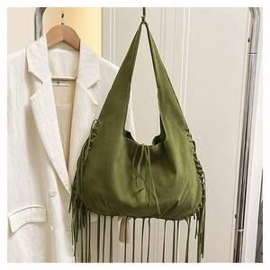 Detail of green suede tote bag featuring bohemian tassels and woven side ties