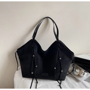 Détail du sac cabas noir avec cordons décoratifs et perles en métal argenté brillant