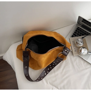Detail of mustard suede tote bag featuring dark brown grommet leather straps and zip top