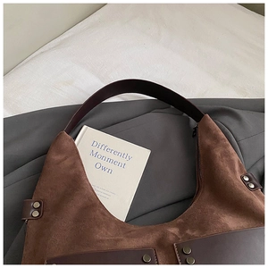 Detailaufnahme der braunen Wildledertasche mit Retro-Nieten und Lederriemen im Vintage-Stil