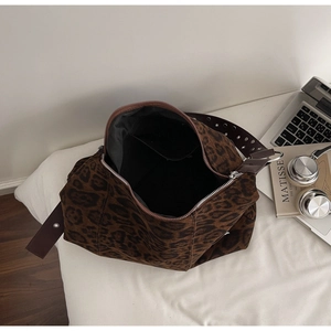 Detail view of leopard print tote bag with metal zipper and studded shoulder strap