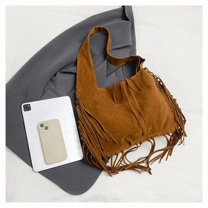 Detail view of large brown suede tote bag with long bohemian tassels and spacious interior