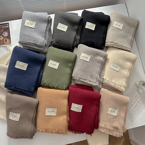 Solid color knitted winter scarves with tassels and brand labels in multiple vibrant colors