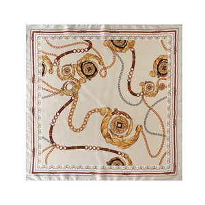 Close-up of silk scarf featuring golden chains and baroque patterns on beige fabric