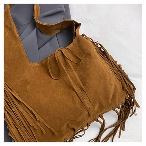 Detail shot of brown suede fringe tote bag featuring long tassels and decorative lacing