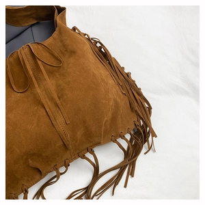 Close-up detail of brown suede tote bag featuring fringe tassels and textured finish