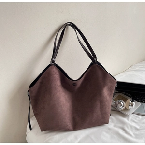 Détail d'un grand sac cabas en daim marron avec ordinateur portable et des livres