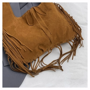 Close-up of caramel suede tote bag featuring long fringes and a side bow detail