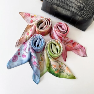 Floral print square silk scarves in pink and blue shown with a black handbag
