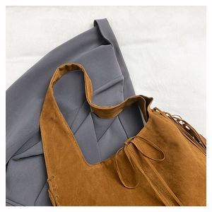 Detailed close-up of brown suede tote bag with fringe tassels and tie closure