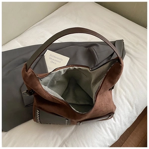 Detailansicht der braunen Wildleder-Tragetasche mit Metallnieten und Fischgrätenfutter