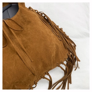 Close-up of caramel suede tote bag featuring bohemian tassels and braided edge details