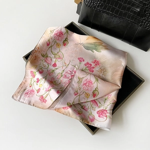 Detailed macro view of pink rose floral silk scarf neatly folded in a black gift box