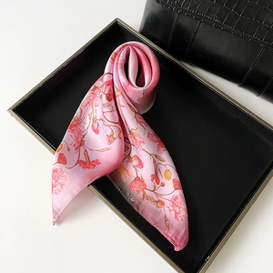 Close-up of pink carnation print silk scarf folded on a minimalist black tray