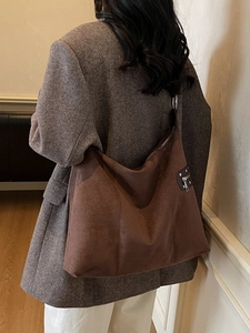 Brown suede tote bag with zipper and rivets shown on model in grey suit for daily commute