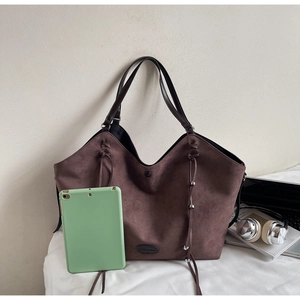 Détail du sac cabas en daim marron foncé avec franges et perles métalliques sur fond blanc