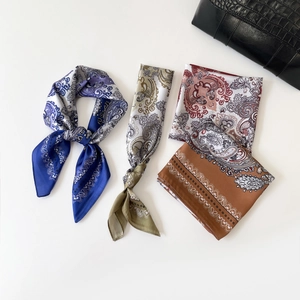 Three elegant paisley silk scarves in navy, green and pink shown with a stylish black bag