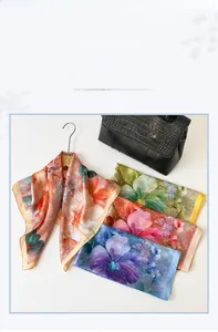 Detail showing assorted floral silk scarves with soft sheen on a wooden hanger