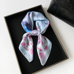 Detail view of light blue floral silk scarf with rose print in a black luxury tray