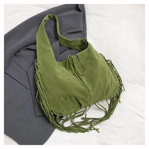 Detail of green suede hobo bag featuring bohemian tassels and relaxed texture