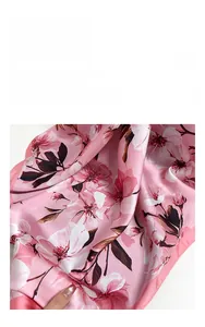 Detailed view of the soft pink satin scarf with white floral patterns and silky texture
