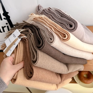 Gros plan d'écharpes douces aux tons terreux montrant les franges et la texture du tissu