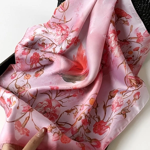 Pink floral silk scarf with rose print displayed on a black textured background