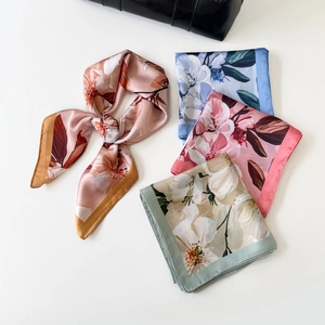 Flat lay view of various floral satin scarves with smooth silk texture and soft shine