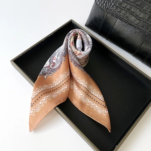 Detailed macro view of the silky paisley pattern scarf placed in a stylish black tray