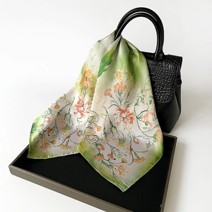 Floral print square silk scarf with orange roses draped over a black luxury handbag