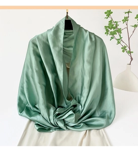 Detalle del chal de satén verde salvia con textura sedosa y una caída elegante y fluida