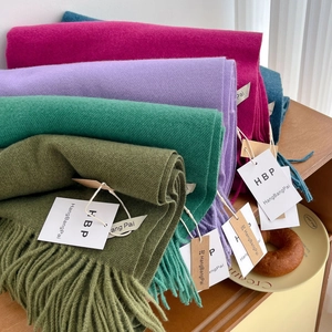 Détail de foulards unis doux avec de longues franges et étiquettes de marque sur bois