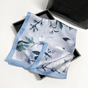 Detail of silk square scarf with magnolia floral print on elegant blue satin fabric