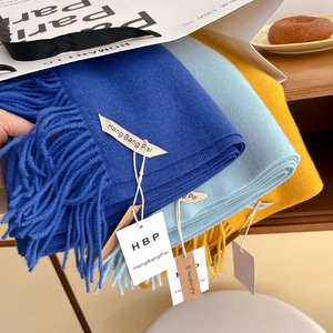 Détail d'écharpes d'hiver colorées avec de longues franges dans un sac en papier